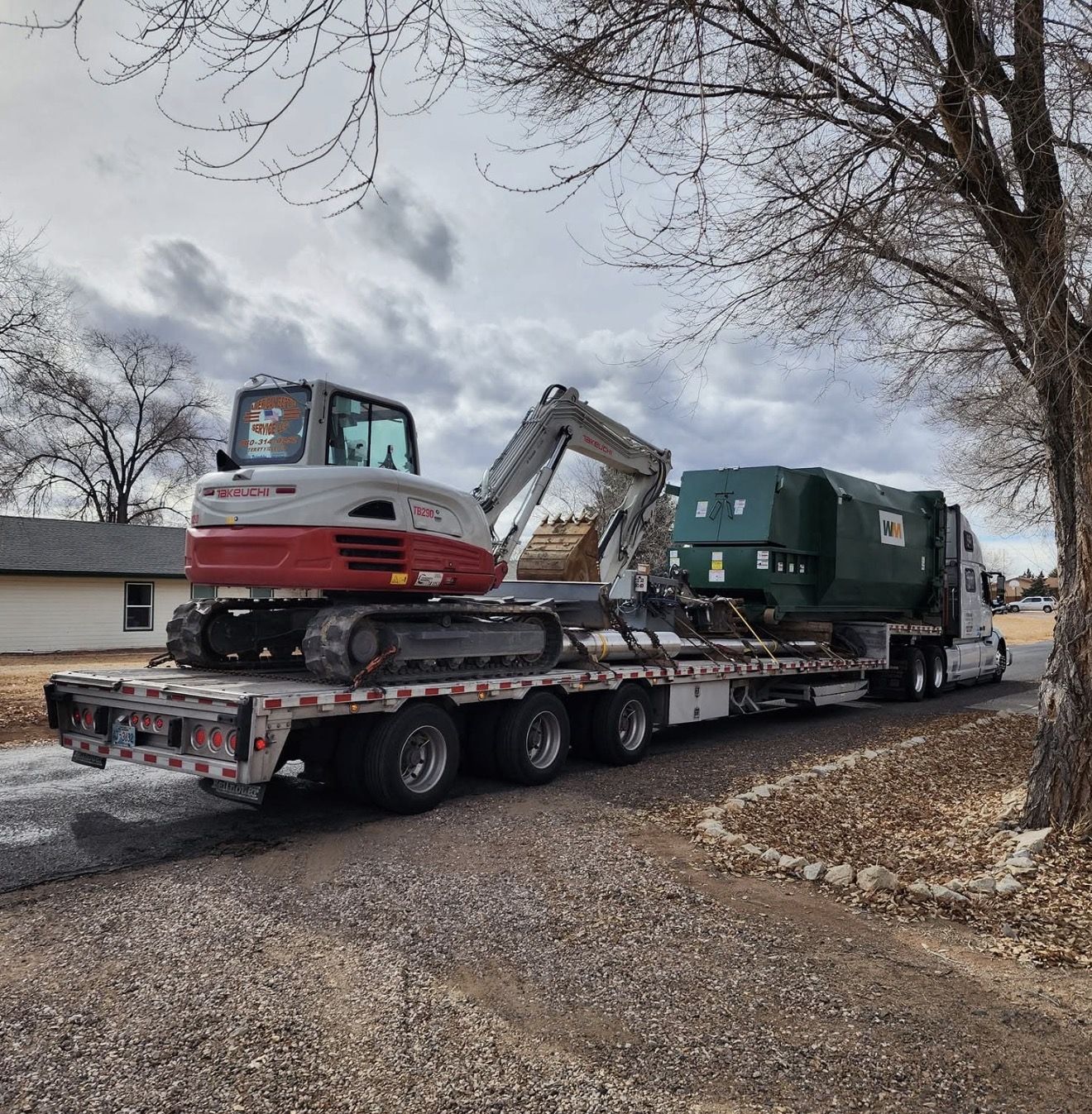 Takeuchi TB230 and a large septic tank on a highway lowboy
