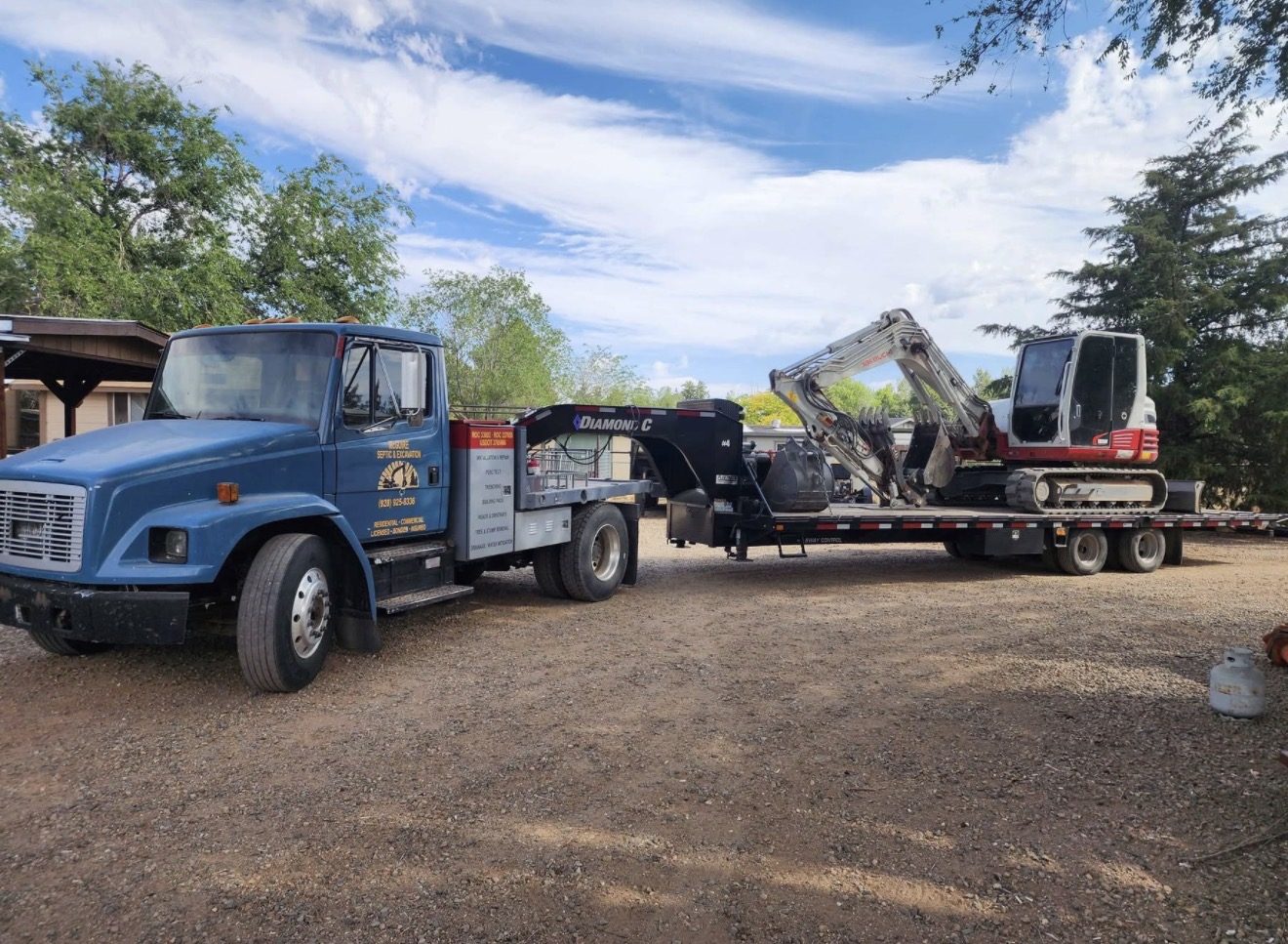 McGuire Septic & Excavation truck hauling a Takeuchi excavator
